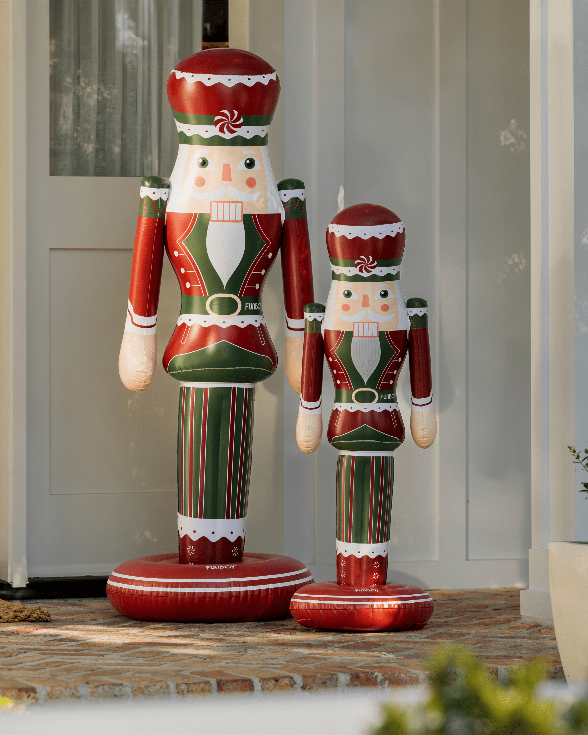 Two inflatable nutcrackers in red, green, and white standing on a porch
