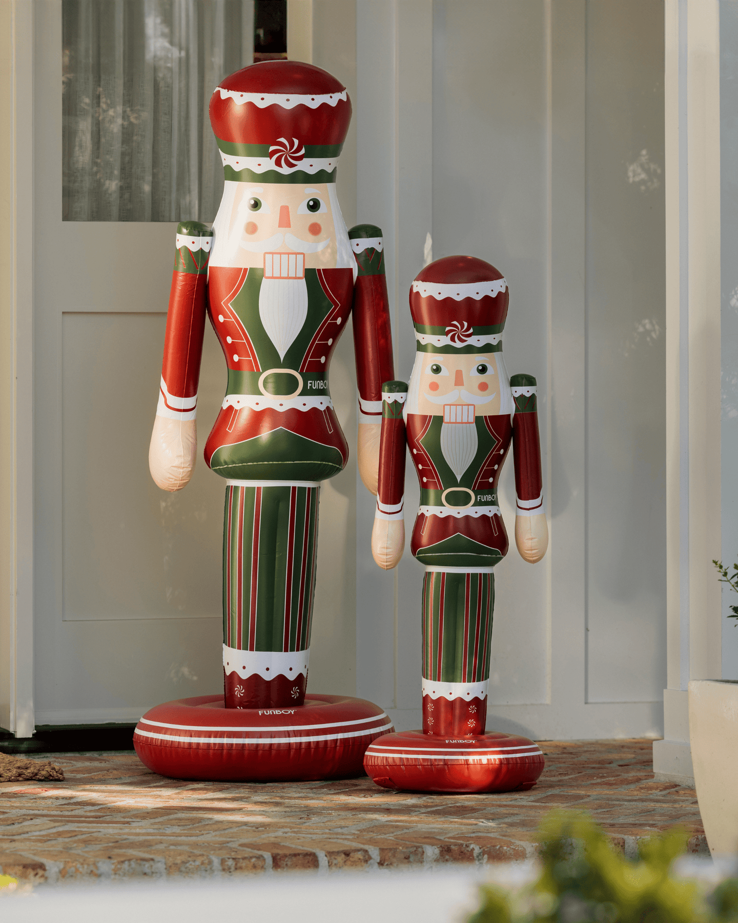 Two inflatable nutcrackers in red, green, and white standing on a porch.
