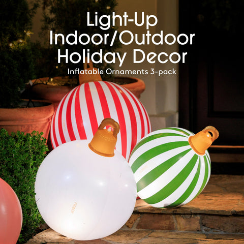 Inflatable holiday ornaments in red, white, green, and orange on a wooden surface outdoors