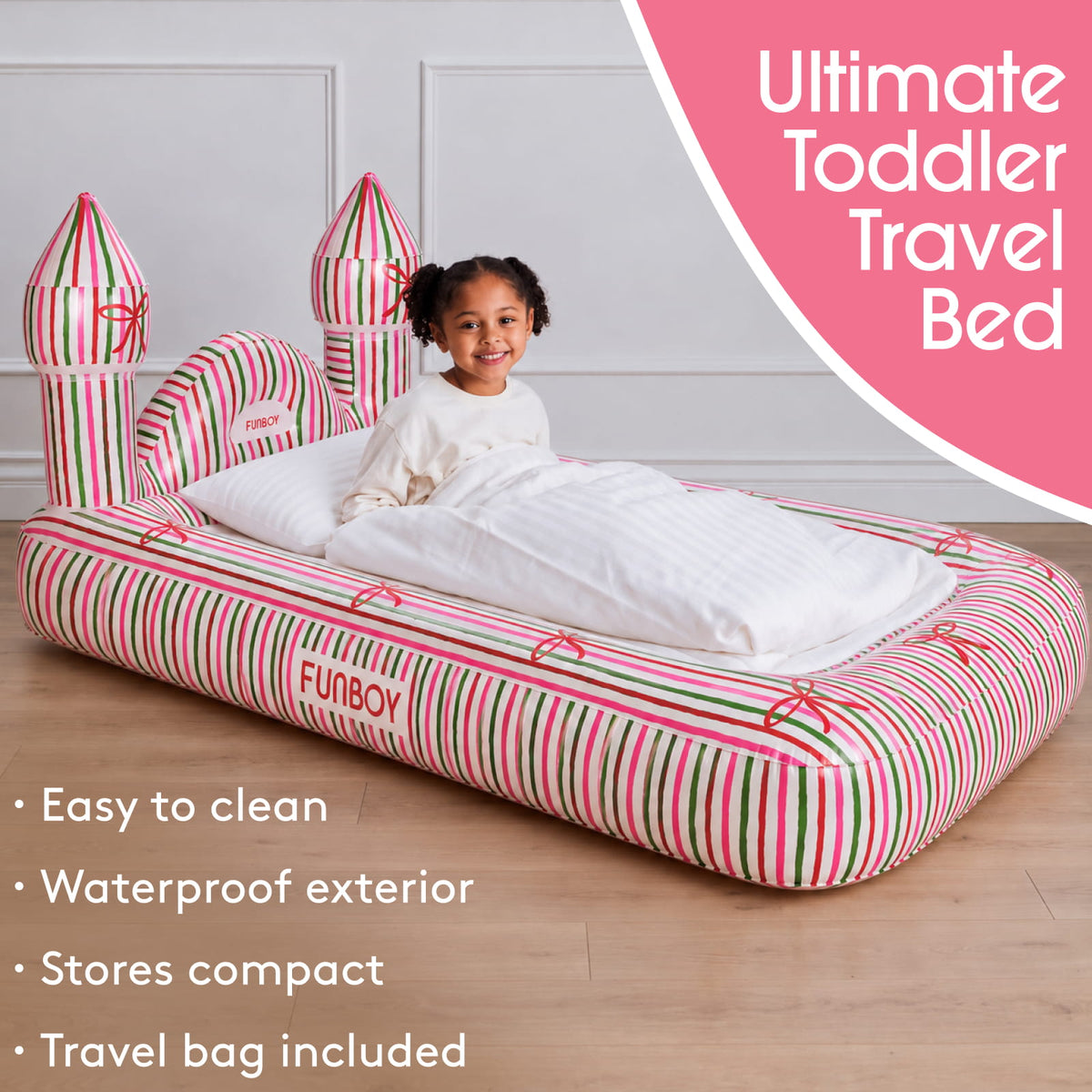 A child sits in an inflatable castle-themed toddler travel bed with pink, green, and white striped sides and a white padded top, shown in a bedroom setting with promotional text overlays.