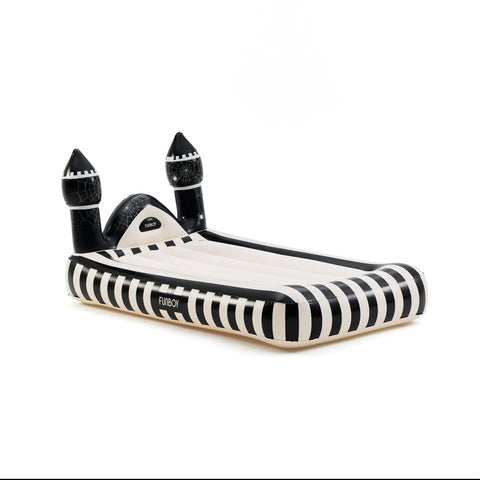 An inflatable castle-shaped pool float with black and white stripes, featuring two black turrets and a slide, shown on a plain white background.