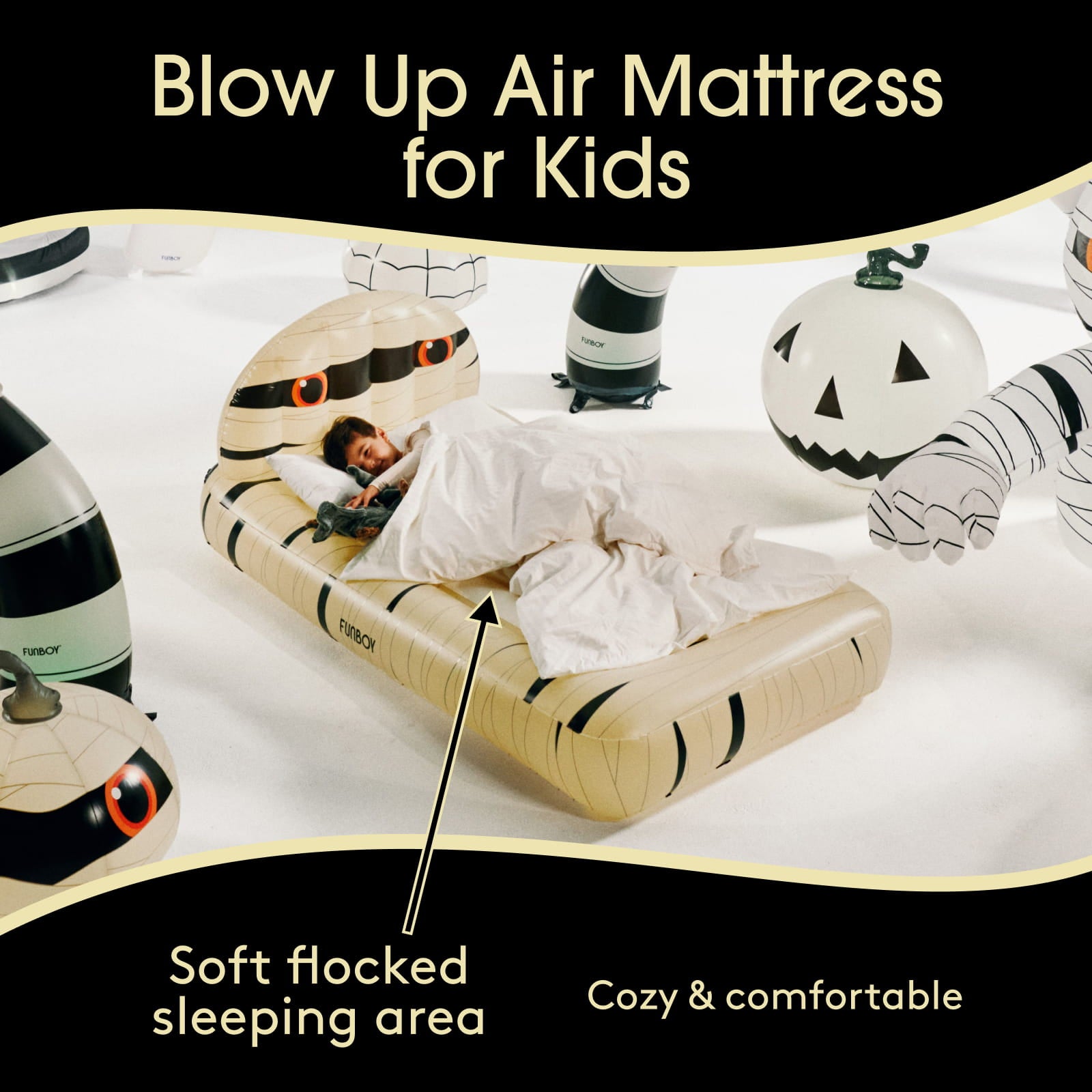 An inflatable mummy-themed air mattress for kids is shown with a child lying underneath and white bedding. The scene includes Halloween props like a jack-o'-lantern and a mummy bandage, with text reading 'Blow Up Air Mattress for Kids' and 'Soft flocked sleeping area.