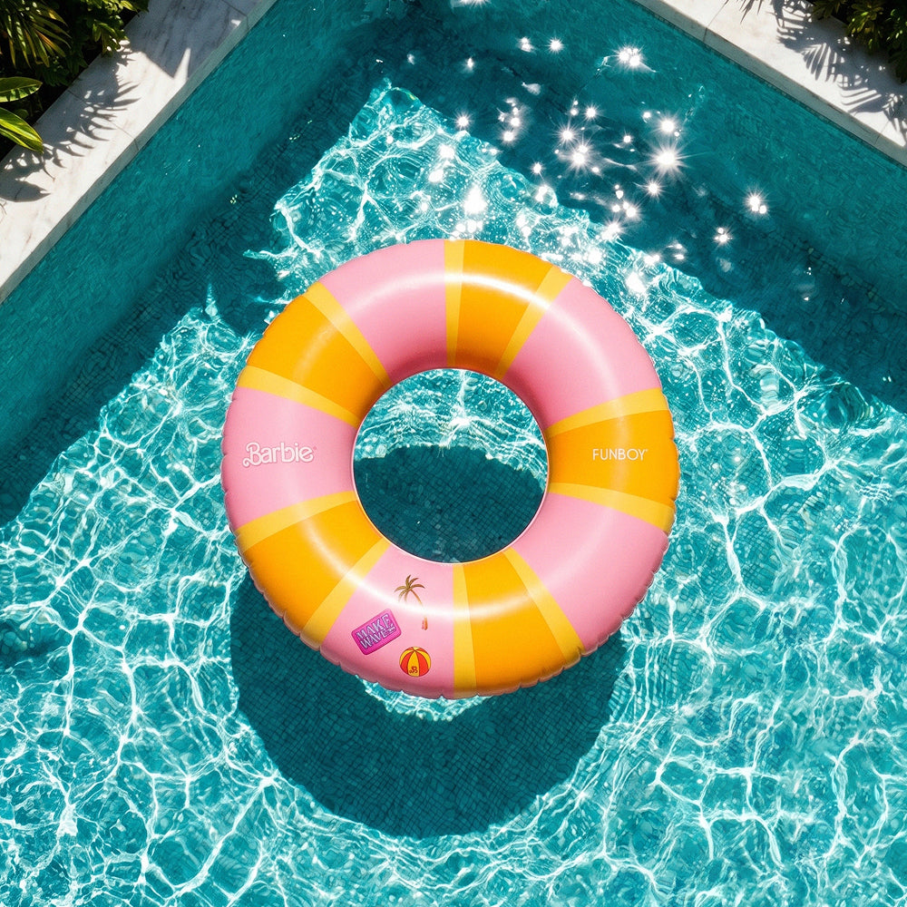 Pink and orange striped Barbie pool float in a pool with sunlight reflecting on the water.