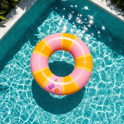 Pink and orange striped Barbie pool float in a pool with sunlight reflecting on the water.