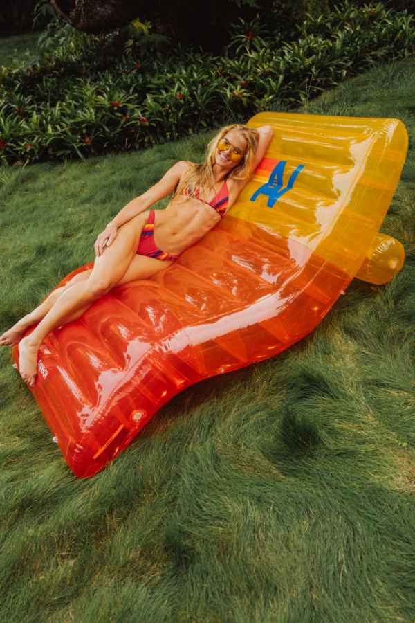 Woman lying on a colorful inflatable pool float in a grassy area