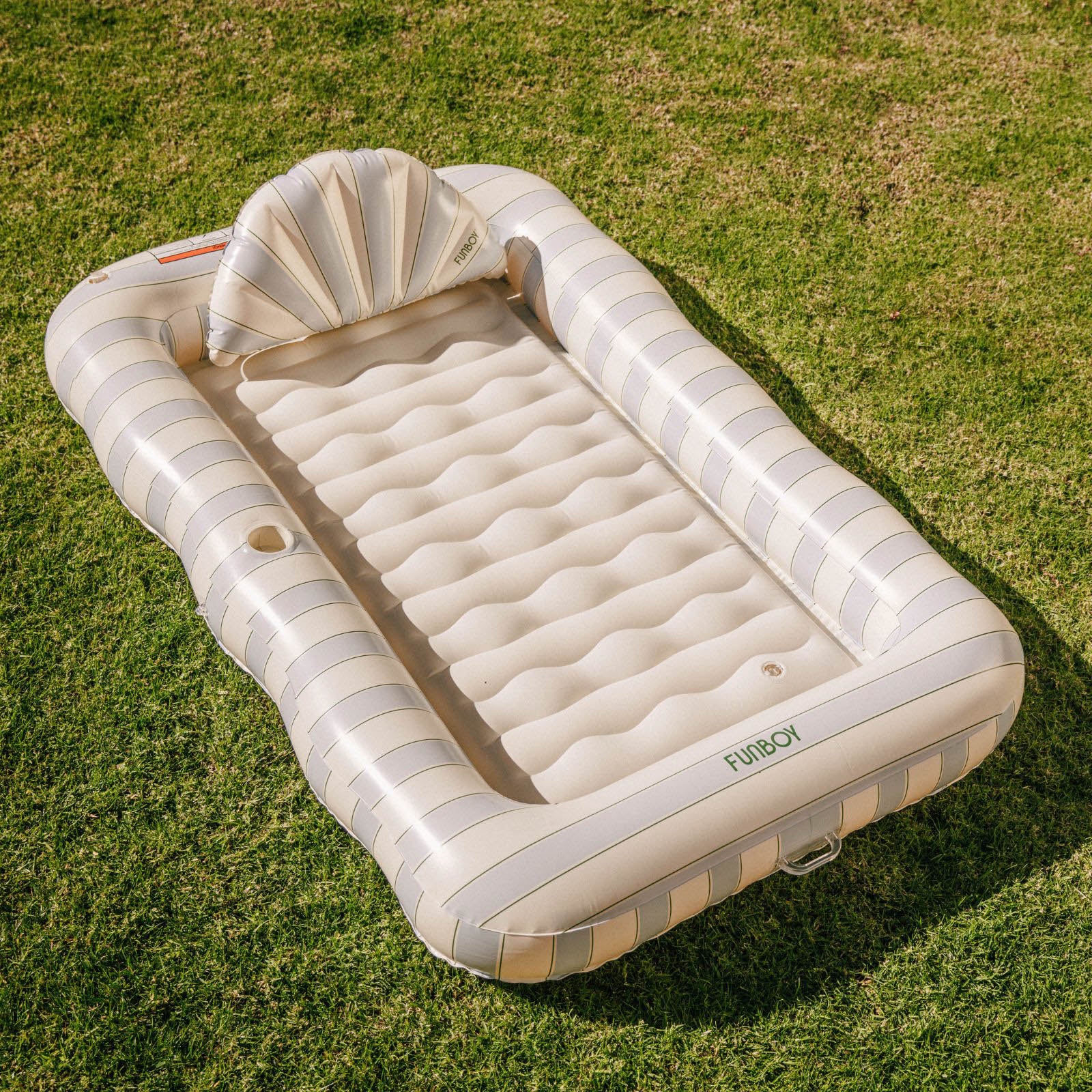 Inflatable air mattress with striped design on a grassy background