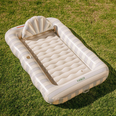 Inflatable air mattress with striped design on a grassy background