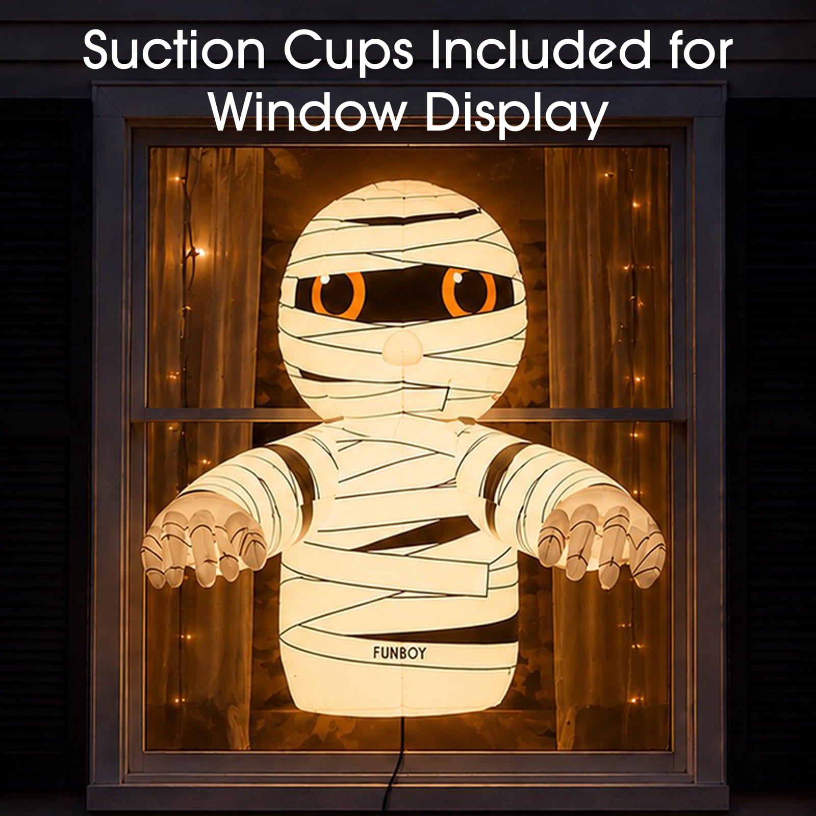 A glowing mummy-shaped window decoration displayed in a window frame, with warm string lights around it and overlaid text reading 'Suction Cups Included for Window Display.' The mummy has white banding, orange eyes, and the name 'FUNBOY' on its torso.