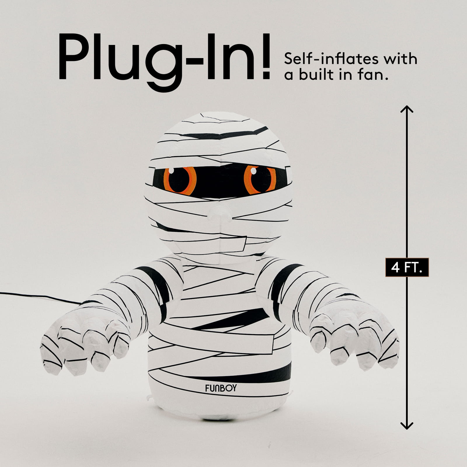 Inflatable mummy toy with orange eyes, wrapped in black and white bandages, shown with text overlays 'Plug-In! Self-inflates with a built in fan.' and a '4 FT.
