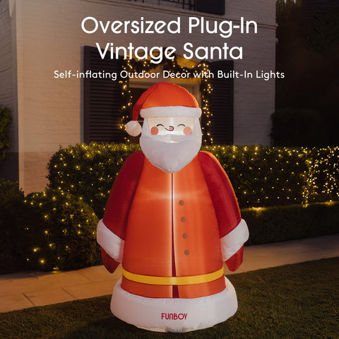 An oversized vintage Santa inflatable outdoor decoration stands on a lawn in front of a house at night. The product is red with white trim and a yellow belt, with built-in lights glowing warmly.