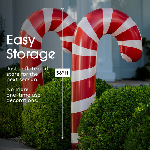 Two large inflatable candy cane yard decorations with red and white stripes, shown outdoors among green shrubs with text highlighting easy storage and 36-inch height.