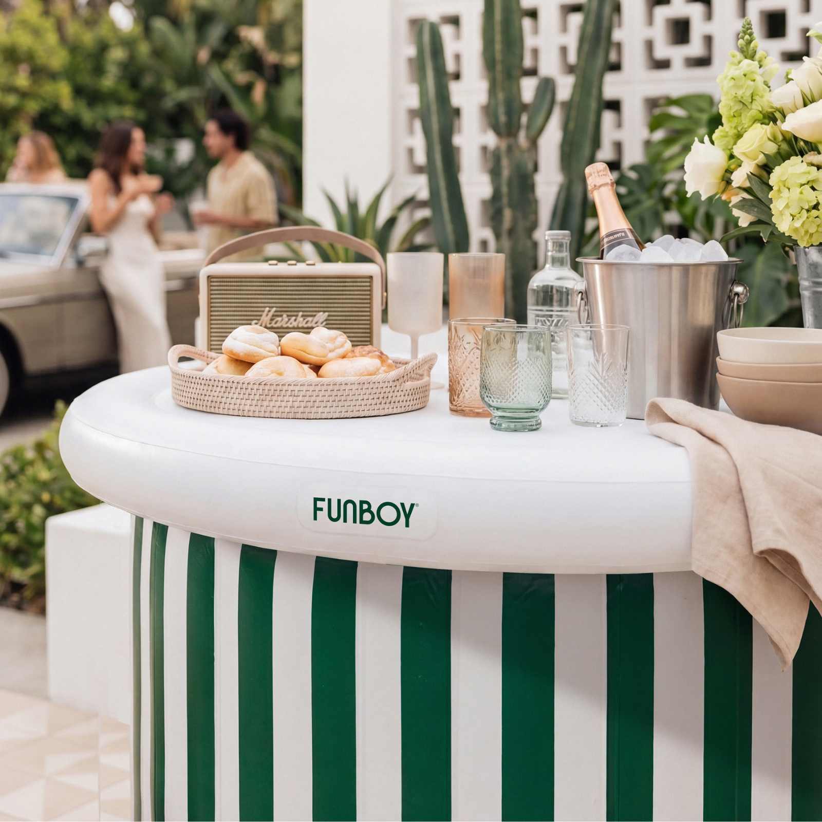 Outdoor setting with a striped bar table, drinks, and snacks, featuring a Funboy branded table.