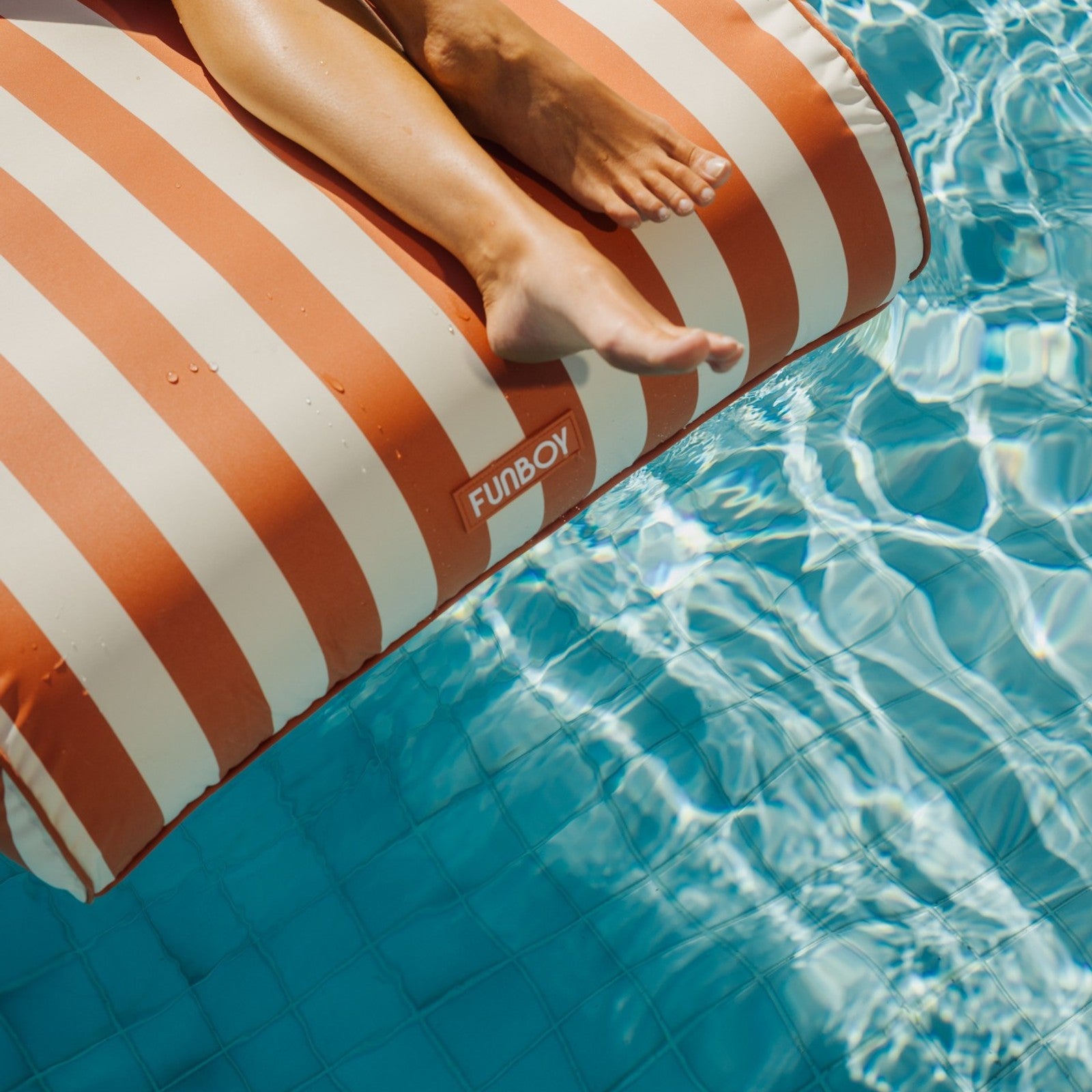Red and white striped pool float with 'Finnboard' logo in a swimming pool.