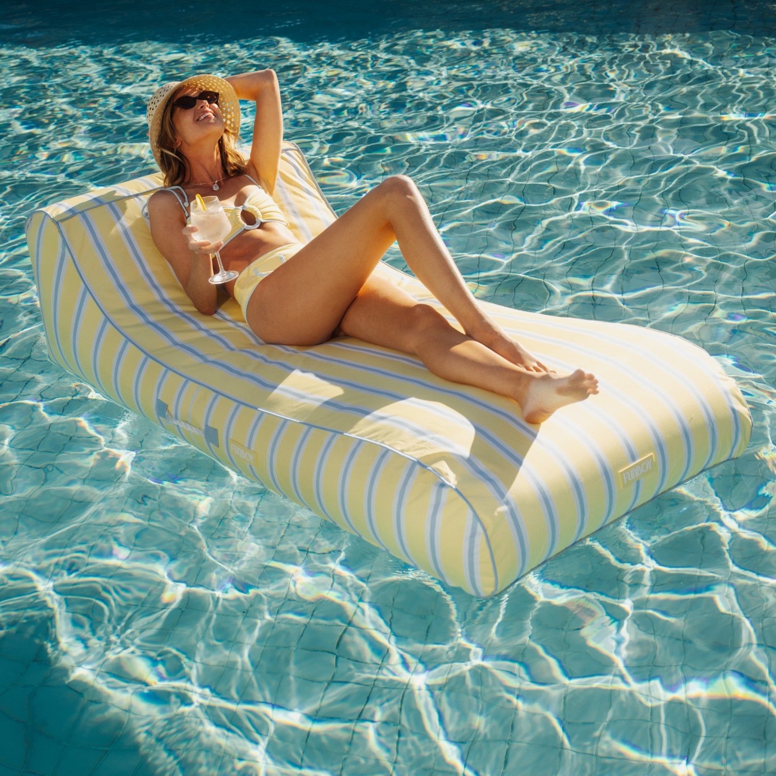 Woman lounging on a striped pool float in clear blue water