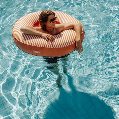 Person floating on a striped inner tube in a pool