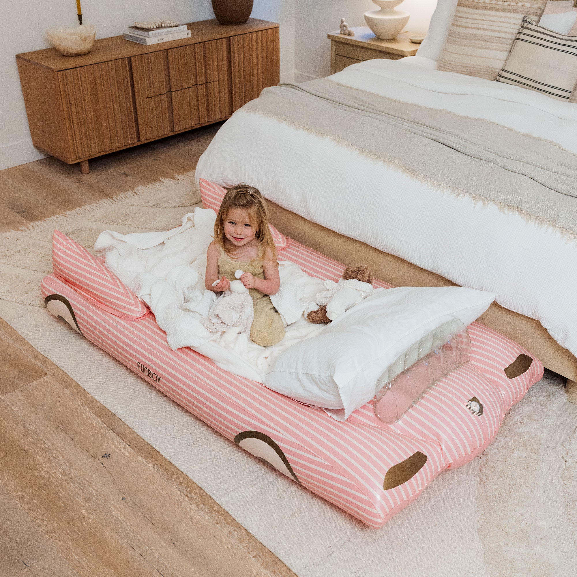 Child relaxing on a FUNBOY pink inflatable kids sleepover bed in cozy bedroom