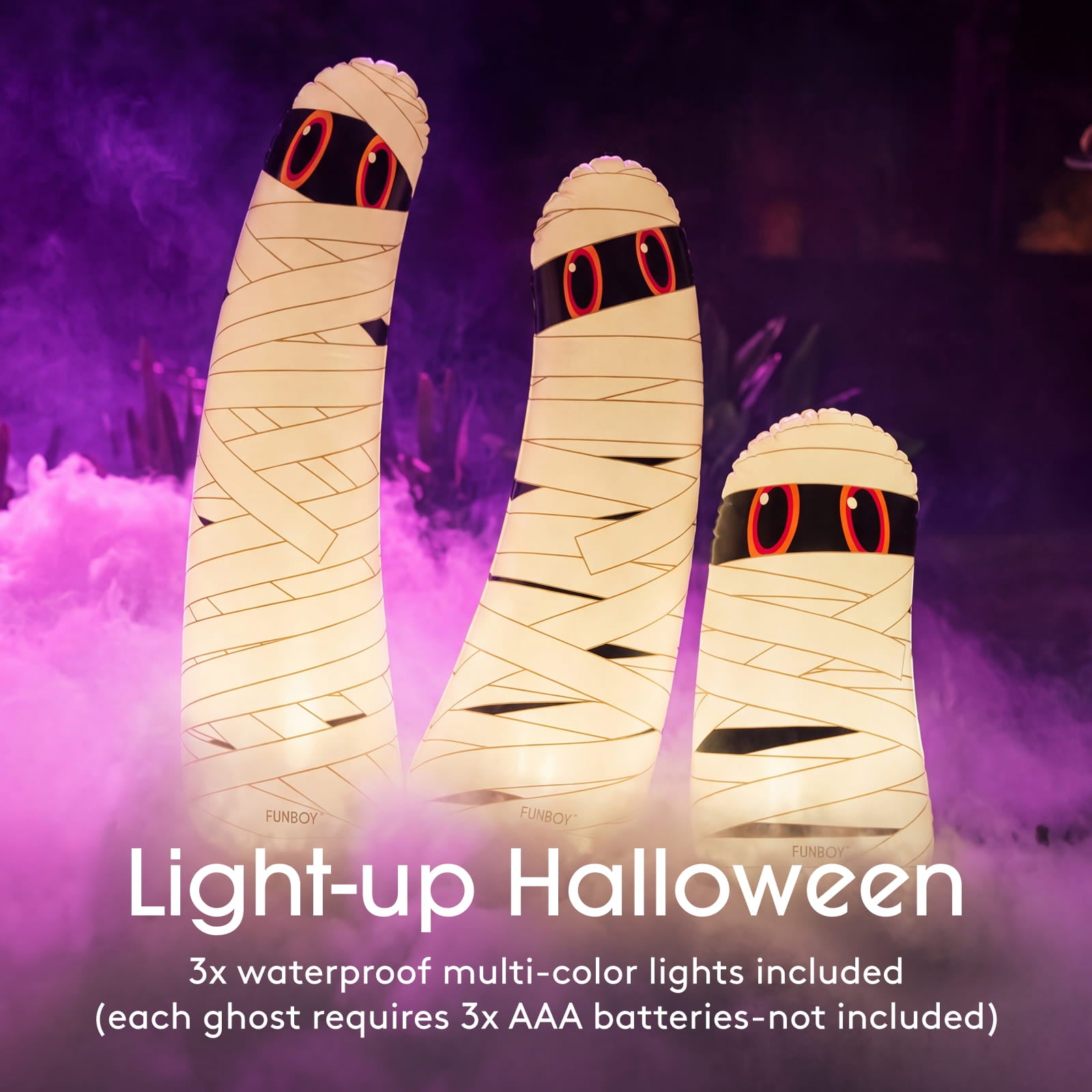 Three inflatable mummy-shaped ghost lights glowing with warm white light, set against a dark purple Halloween-themed background with fog. White text at the bottom reads 'Light-up Halloween' and includes battery information.