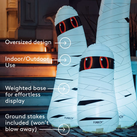 Three illuminated inflatable mummy-shaped party decorations with glowing red eyes and white wrap-like bands, shown outdoors at night with overlaid callout text describing features. The visible brand name FUNBOY appears near the bases of the mummies.