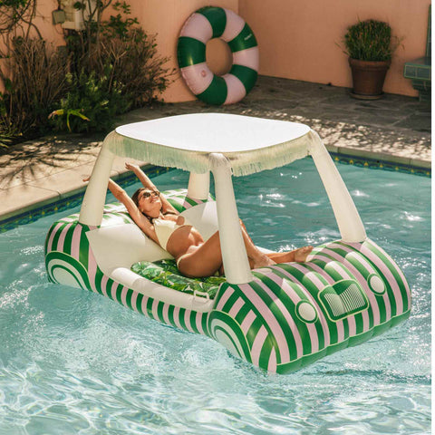 Woman lounging on a green and white striped pool float with canopy in a pool.