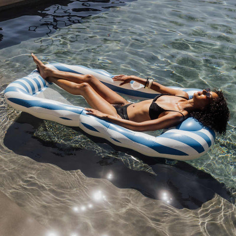 Woman relaxing on a striped pool float in clear water