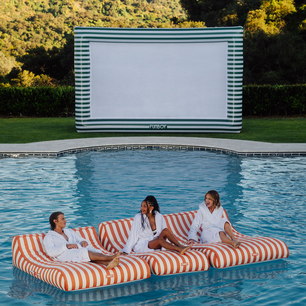 Green & White Inflatable Movie screen with pool floats floating in front of it.