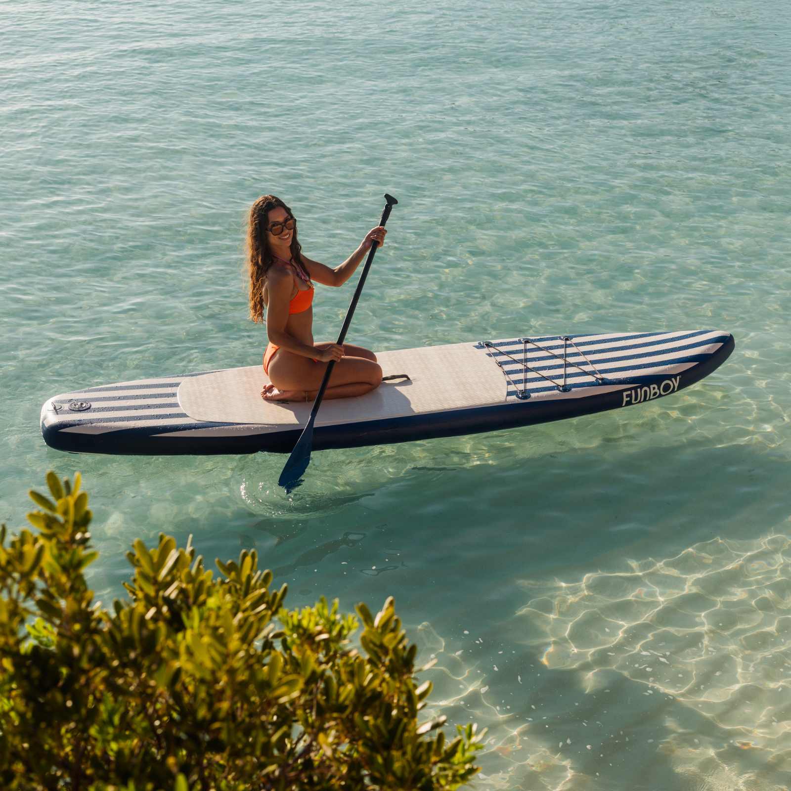 Woman paddleboarding on a clear blue lake with trees in the background