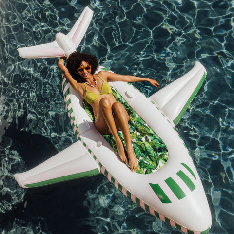 Woman lounging on an inflatable airplane pool float in a pool.