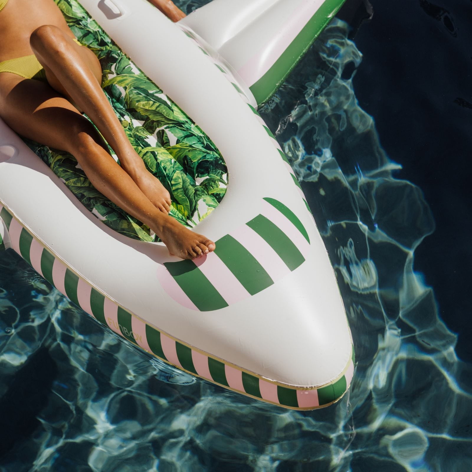 Inflatable pool float with green leaf pattern and striped design in water