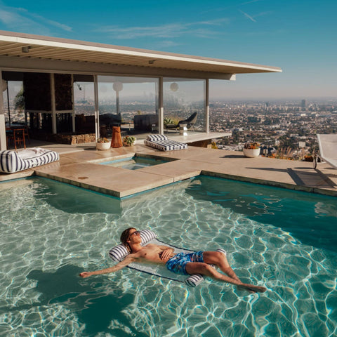 Person lounging by a pool with a cityscape view