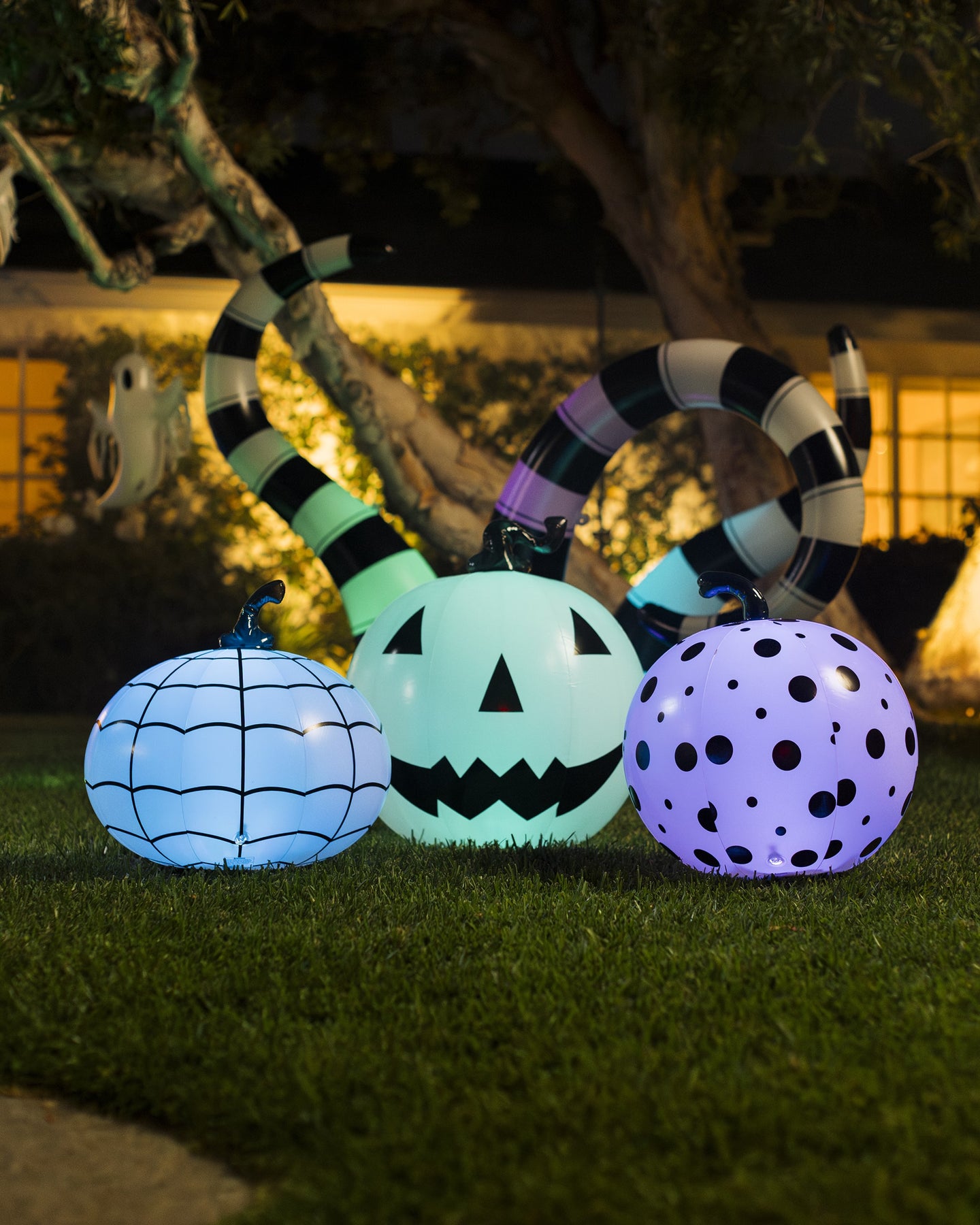 Halloween-themed light up inflatable decorations on grass with a house in the background