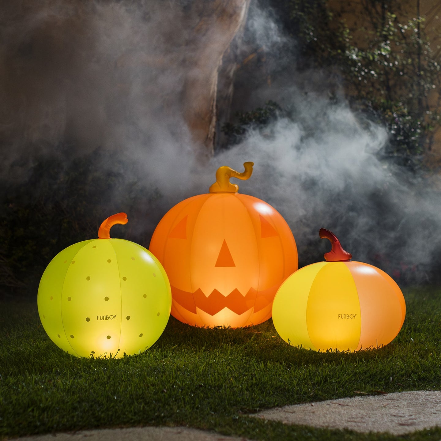 Three inflatable pumpkin lights on grass with a dark background