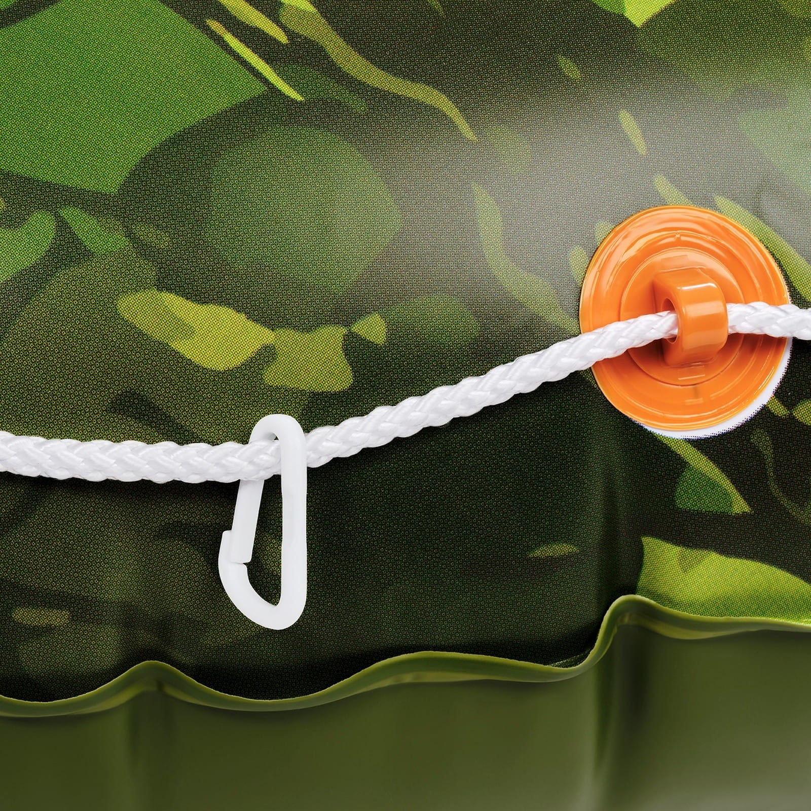 Close-up of a green camouflage tent with an orange rope tie-off and white rope, on a dark green background.