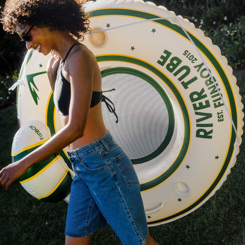 Person holding a large inflatable river tube with branding in an outdoor setting