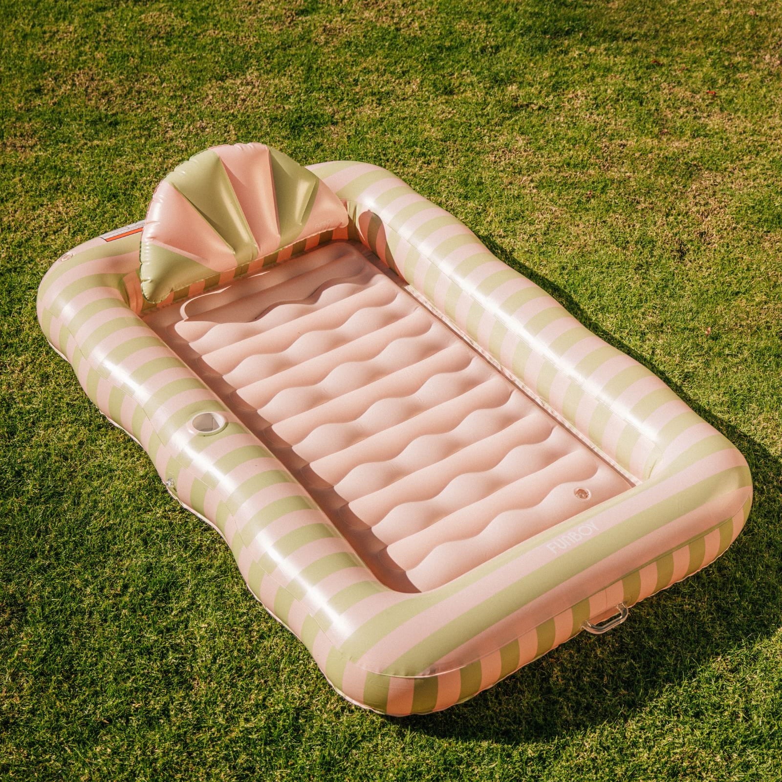 Inflatable pink and green striped pool on grass