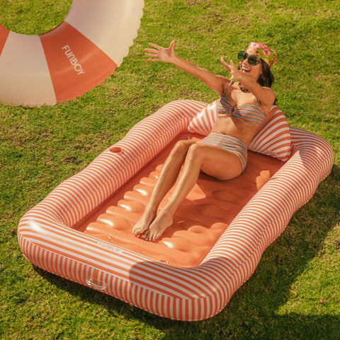 Woman lounging on a striped inflatable pool raft in a grassy area