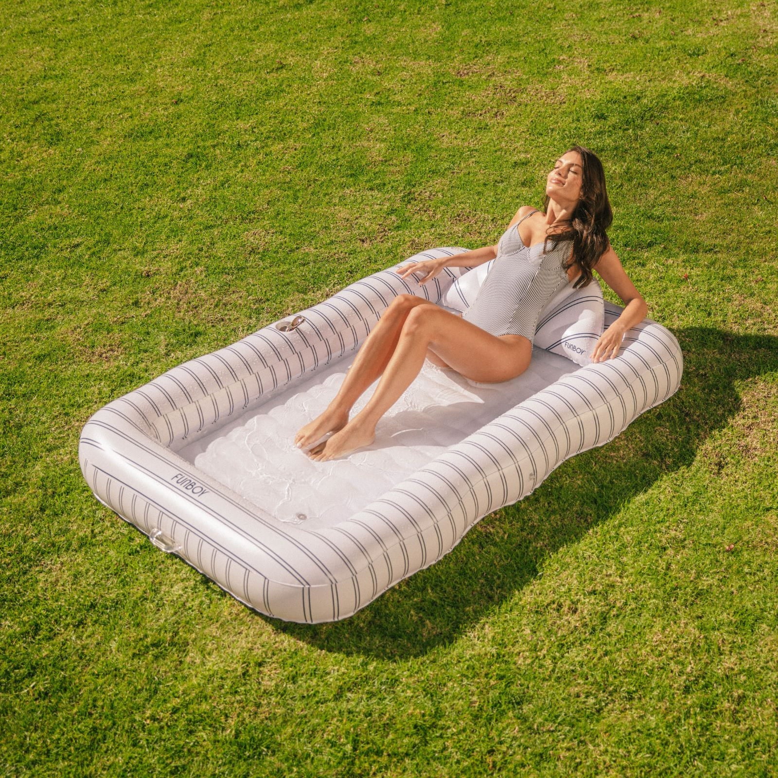 Woman lying on an inflatable tanning lounger in a grassy field