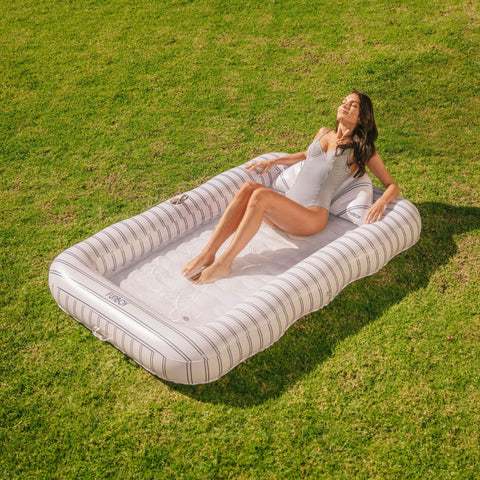 Woman lying on an inflatable tanning lounger in a grassy field