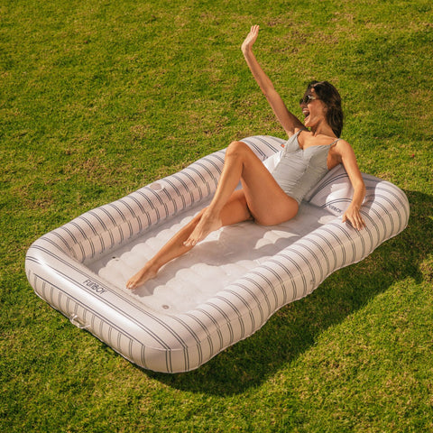 Woman lounging on an inflatable striped pool float in a grassy area