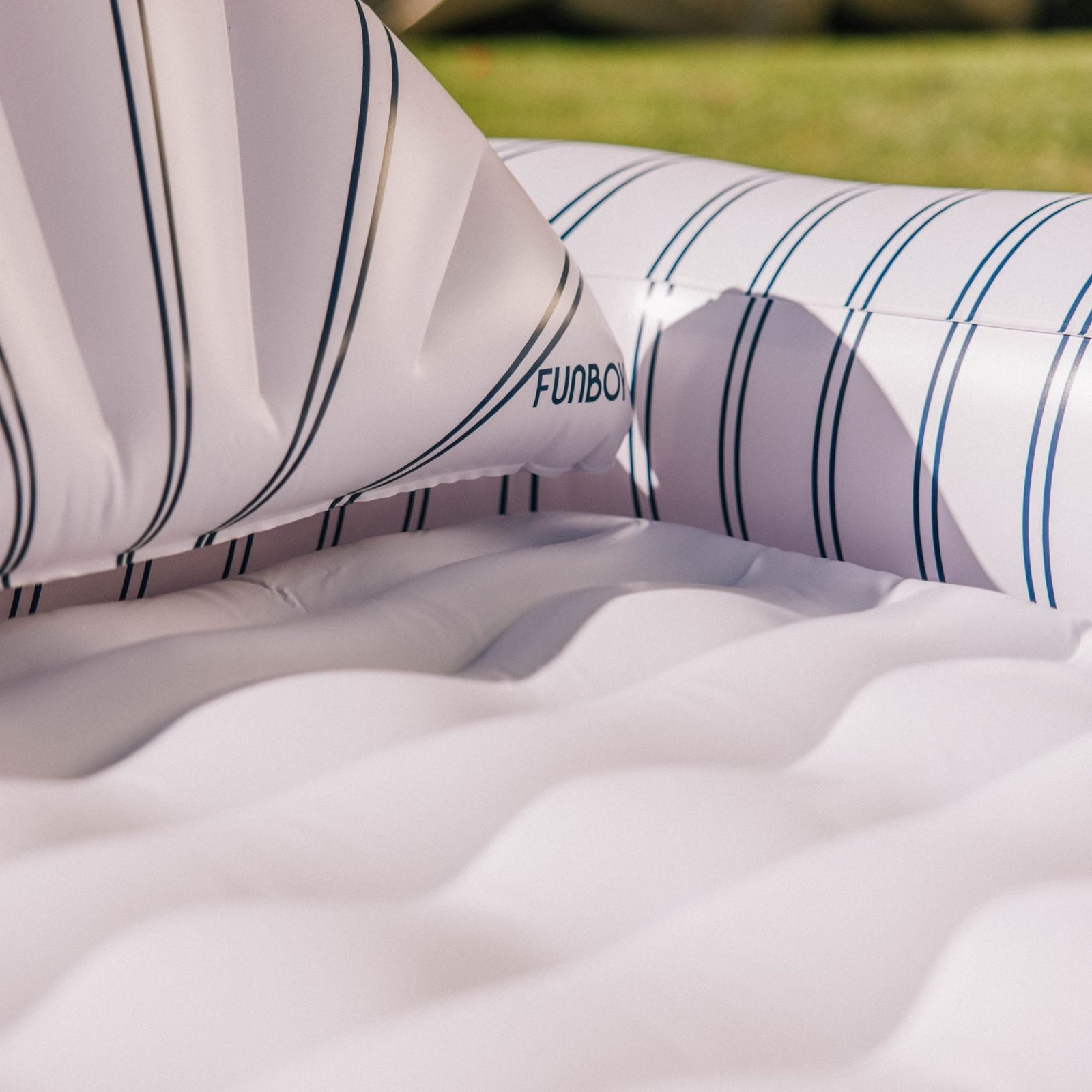 Inflatable pool float with striped pattern on a grassy background