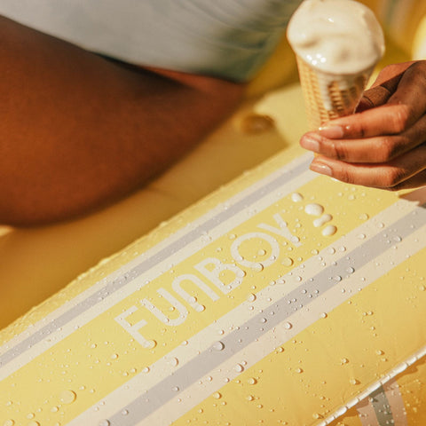 Yellow surfboard with 'FUNBOY' branding on a yellow surface, close-up.