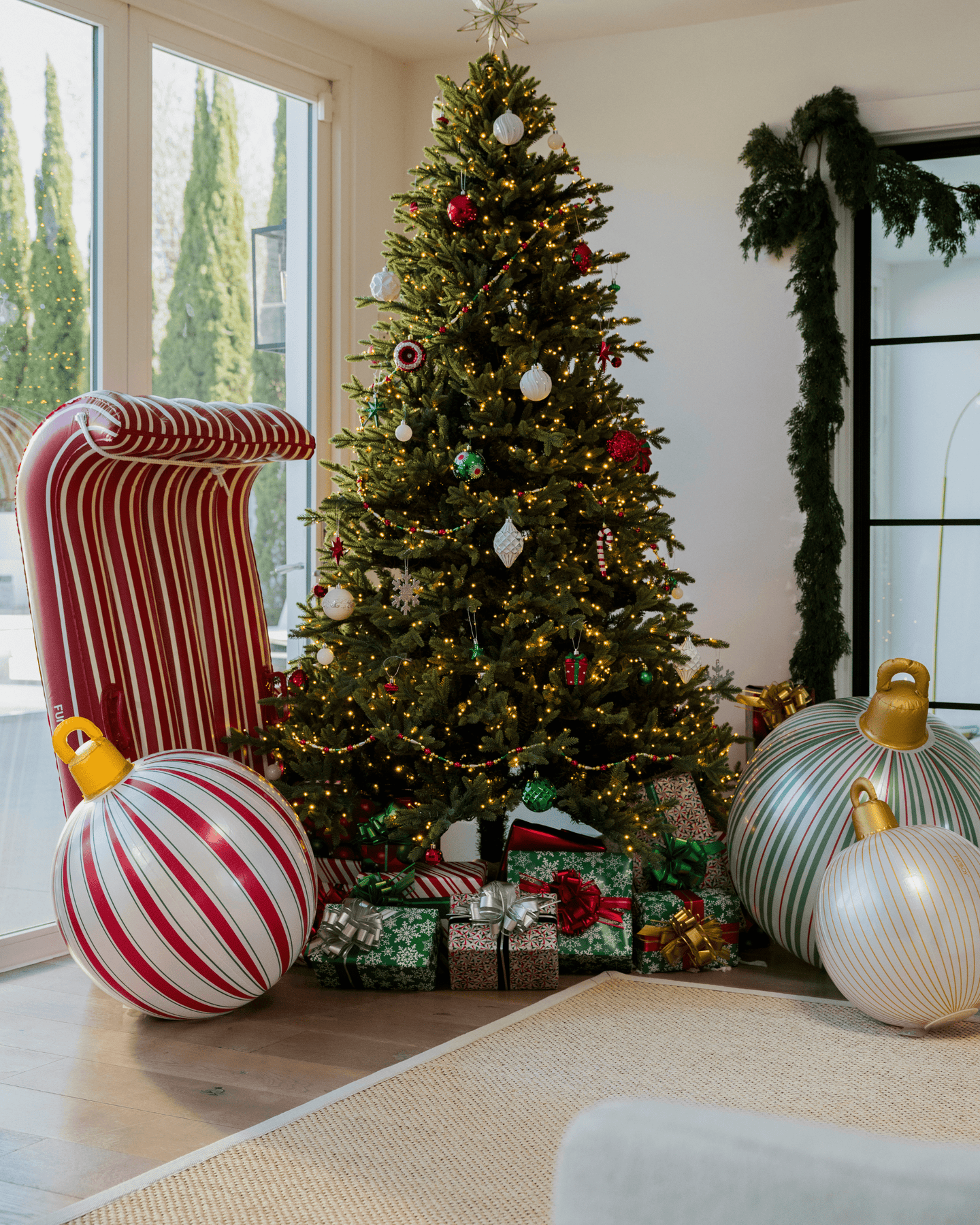 Decorated Christmas tree with ornaments and presents in a living room.