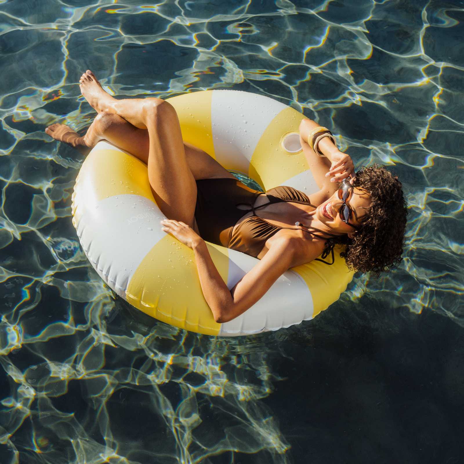 Woman relaxing on a yellow and white inflatable ring in a pool