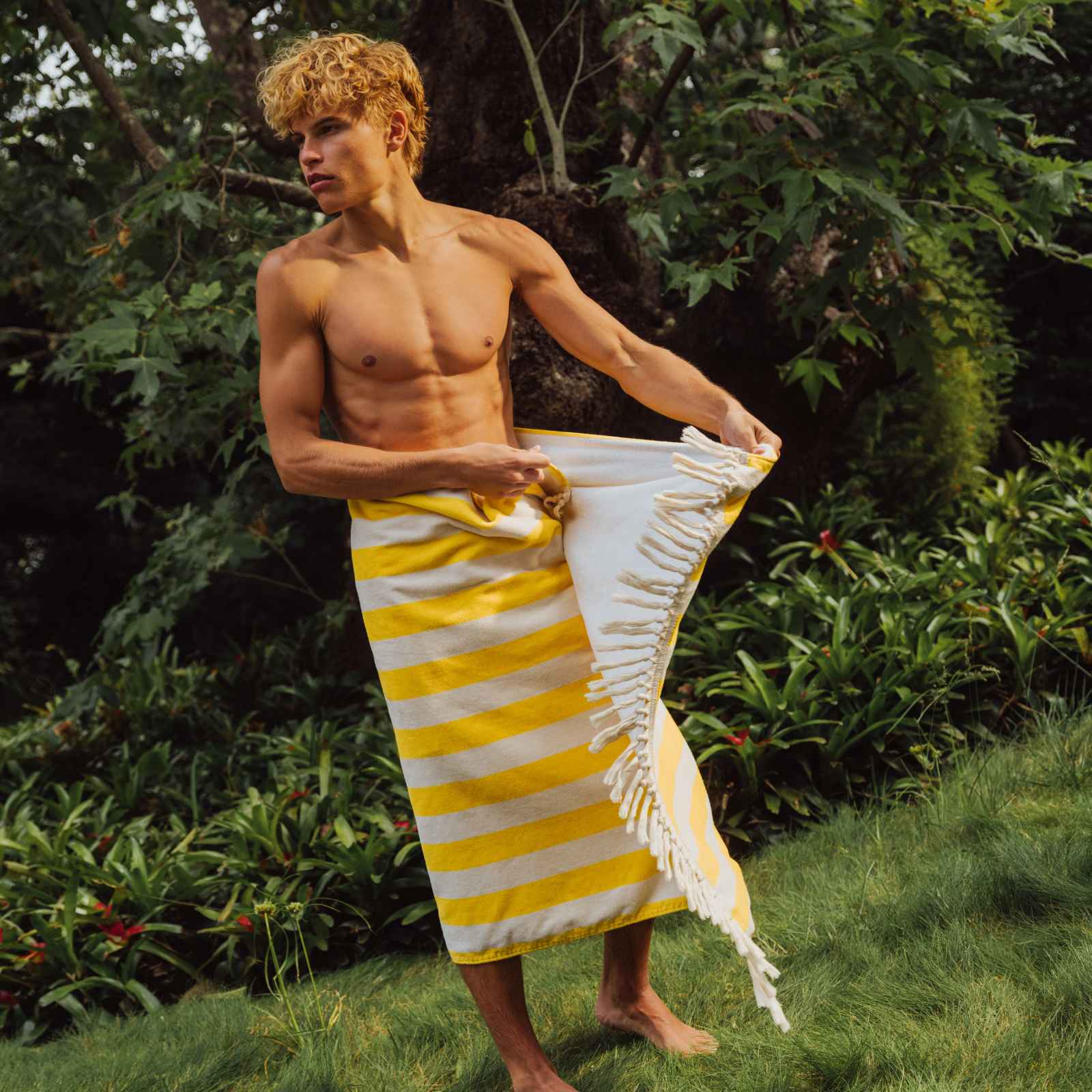 Man holding a yellow and white striped towel in a natural setting
