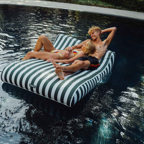 Two people relaxing on a striped inflatable pool float in a pool. XL Green Fabric Lounger